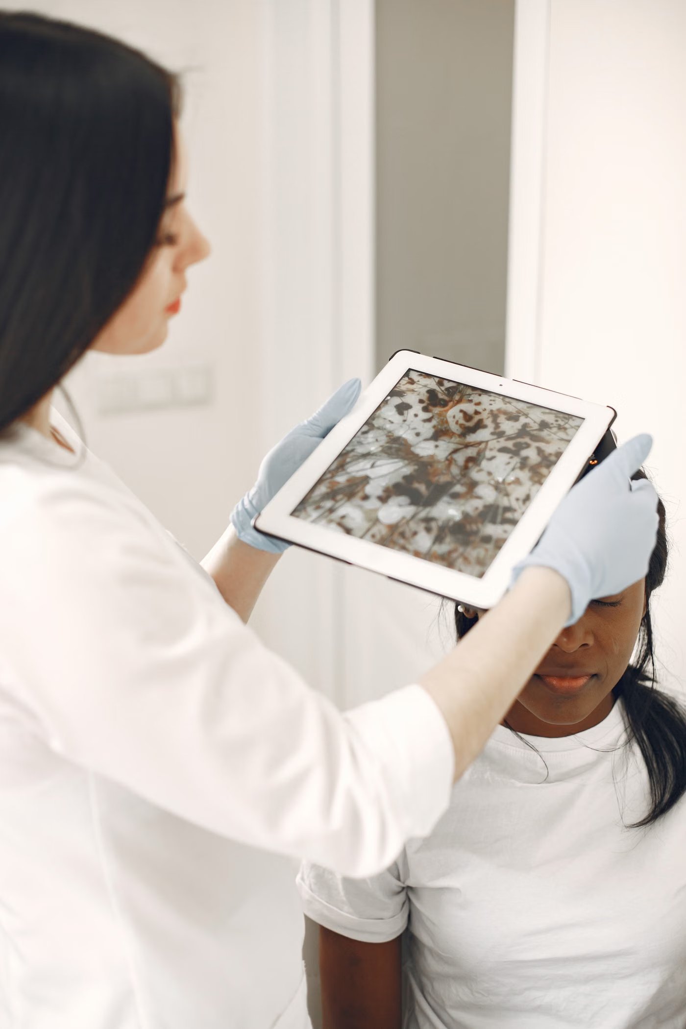 Dermatologin untersucht die Haut eines Patienten