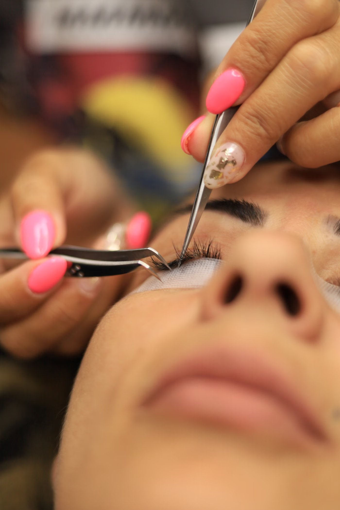 Stylistin trägt Wimpernverlängerung bei einer Kundin auf