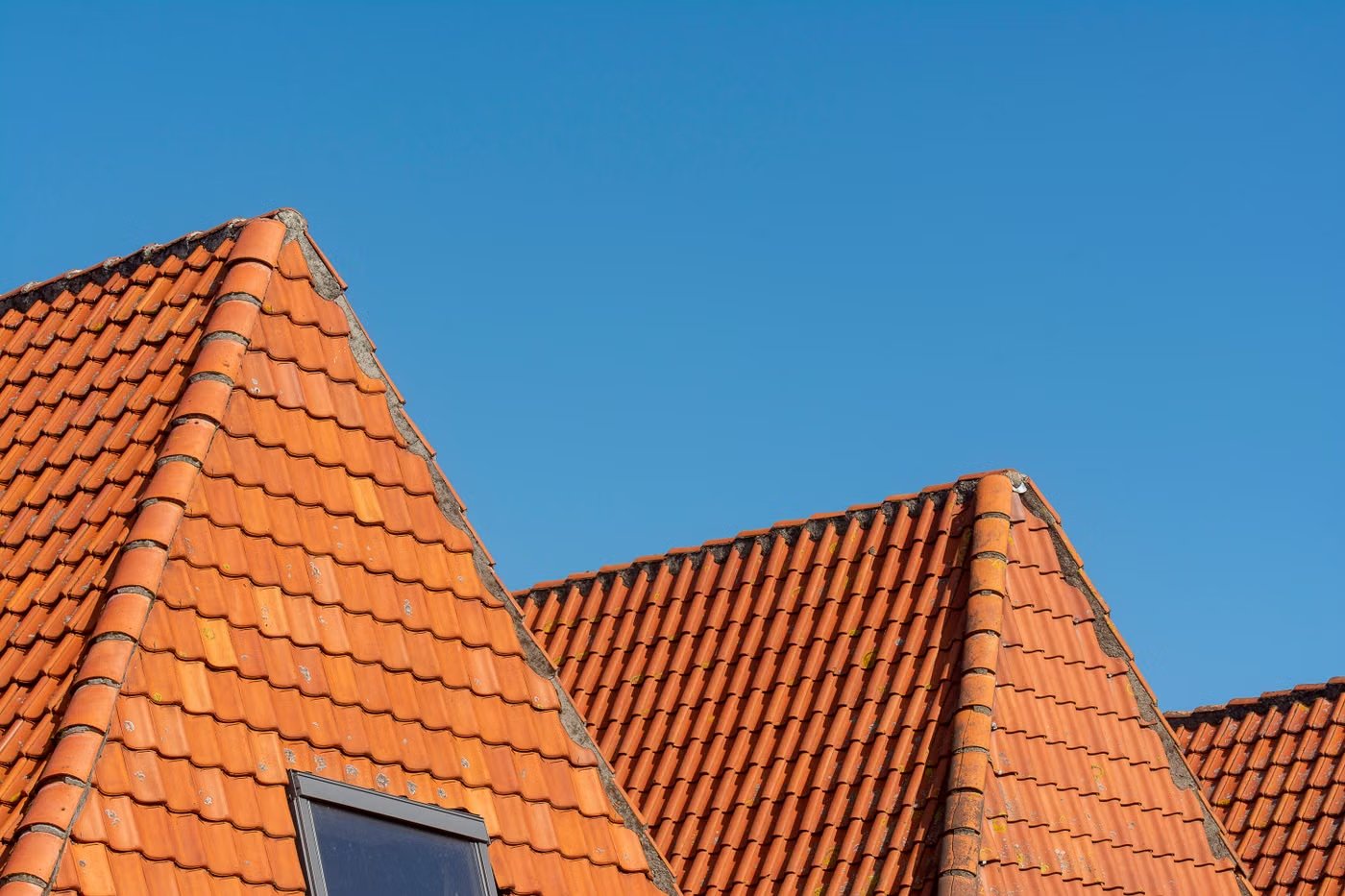 Dachdecker verlegt neue Schindeln auf einem Hausdach